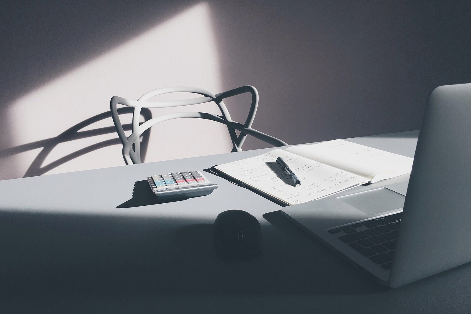 Laptop, notebook and calculator on a bright minimal desk
