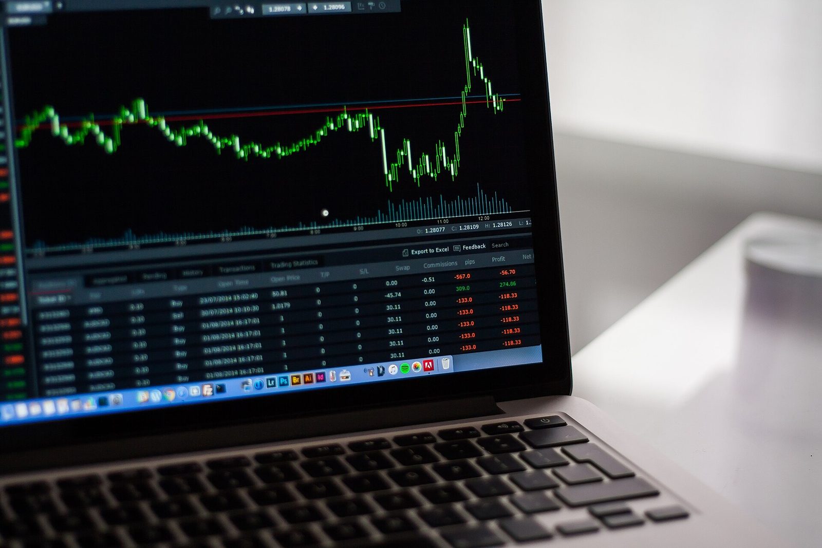 A musician at a desk reviewing a simple cost-per-fan calculation next to an analytics dashboard on a laptop.