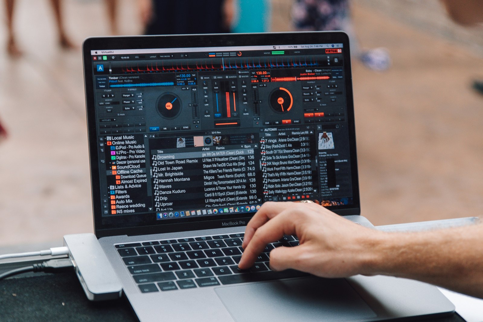 A MacBook Pro showing DJ software next to a DJ controller