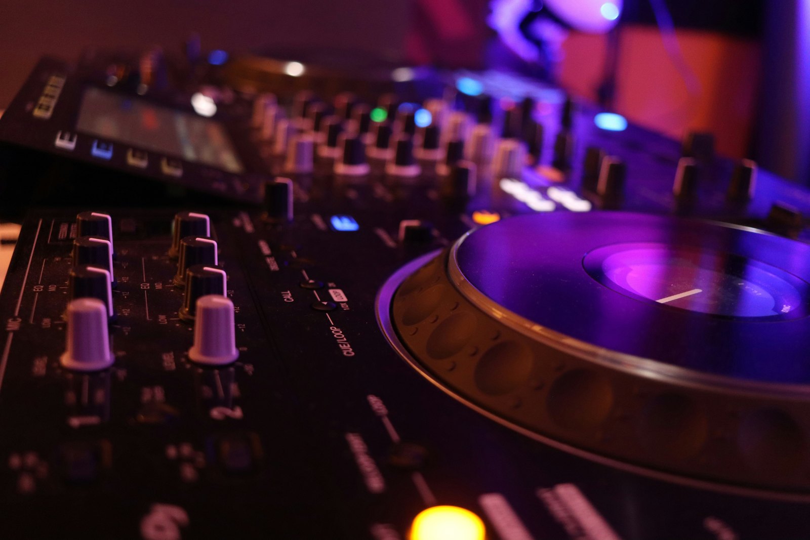 A close up of a DJ's turntable and mixer in low light.