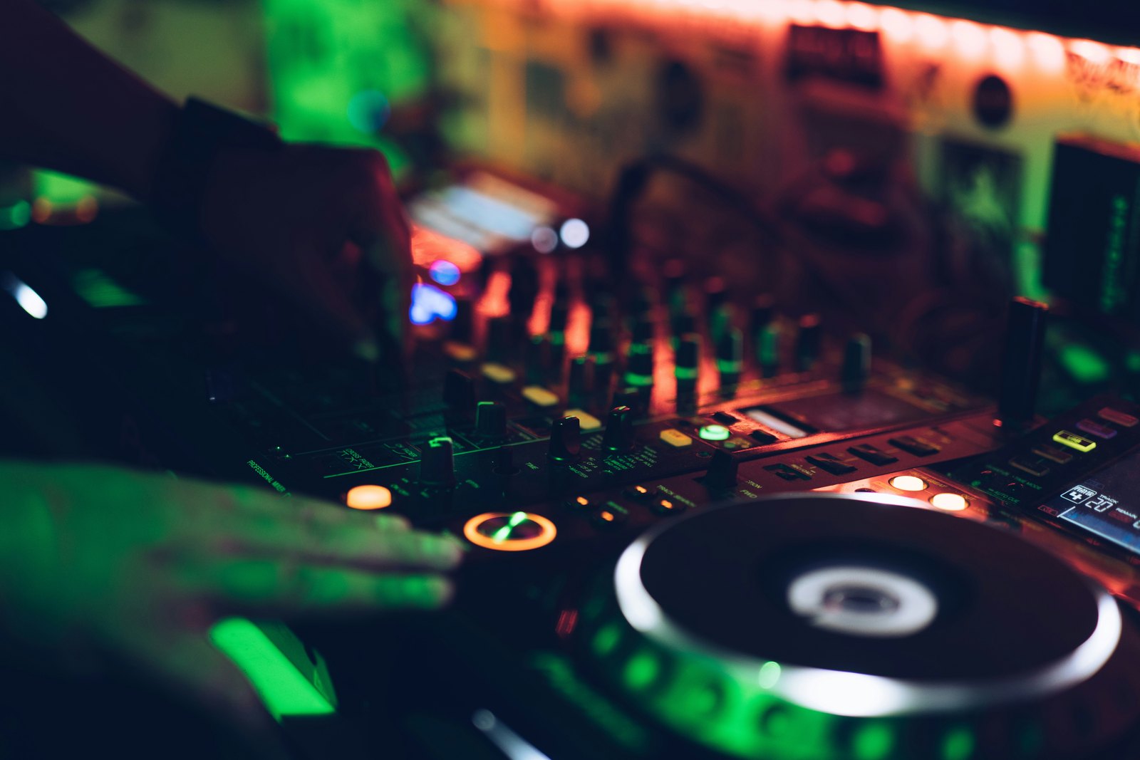 A person using a DJ mixer in a dark nightclub