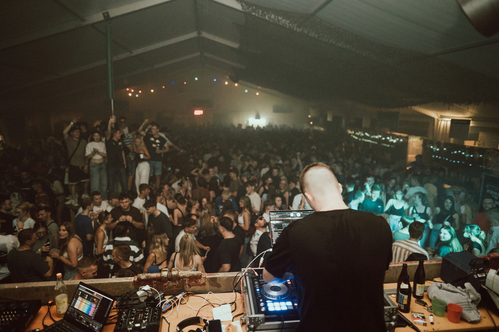 A DJ performing in front of a large crowd at a concert