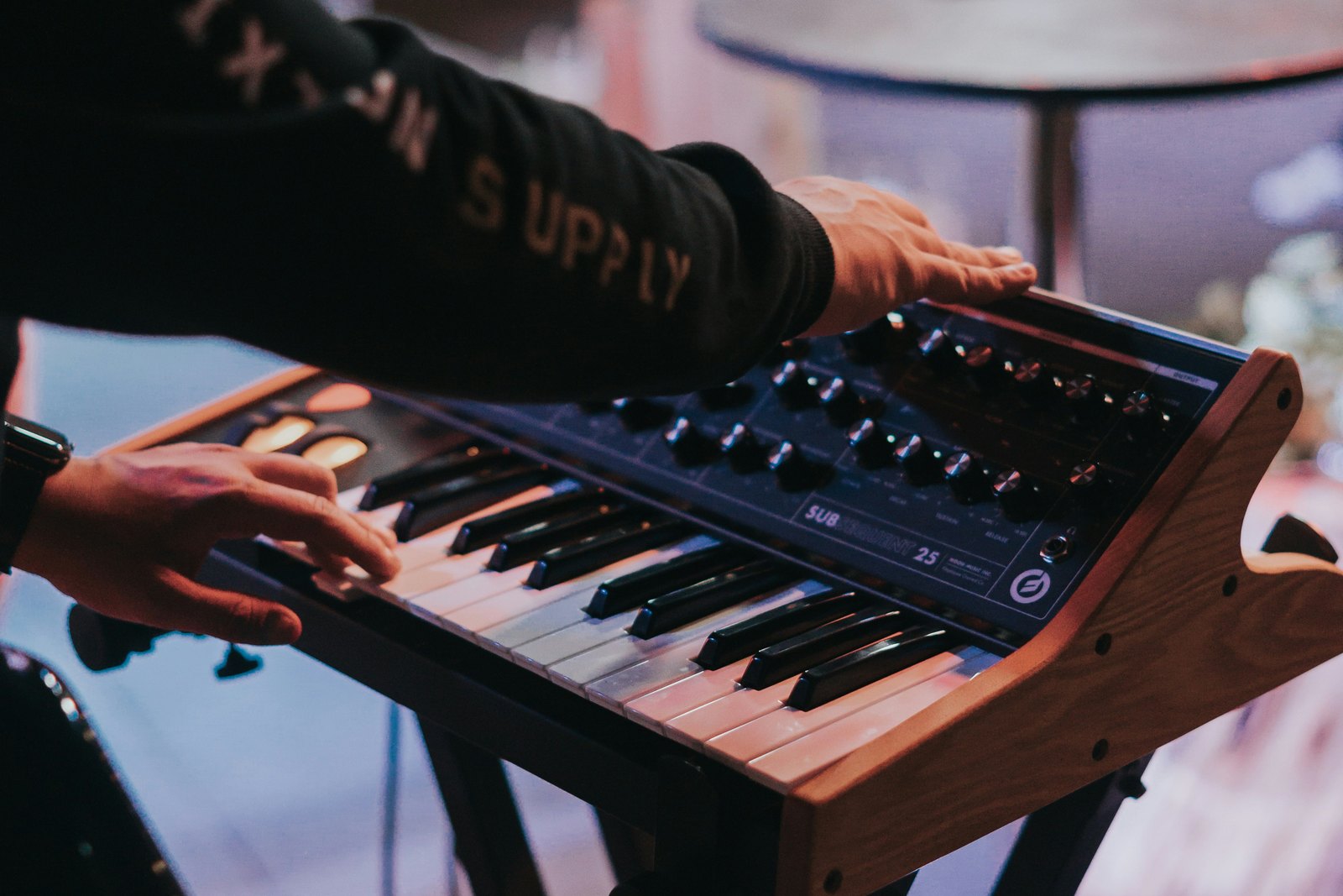 A person playing a synthesizer keyboard in a room.