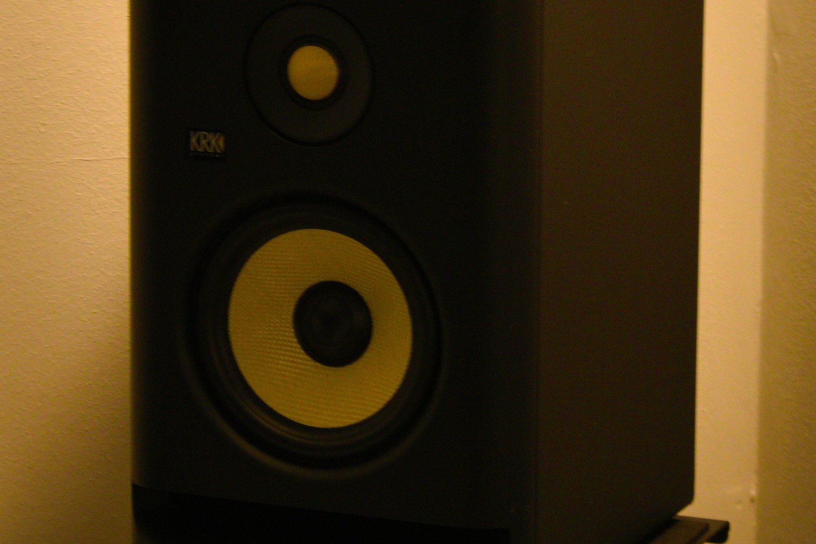 A black studio monitor speaker with yellow accents.