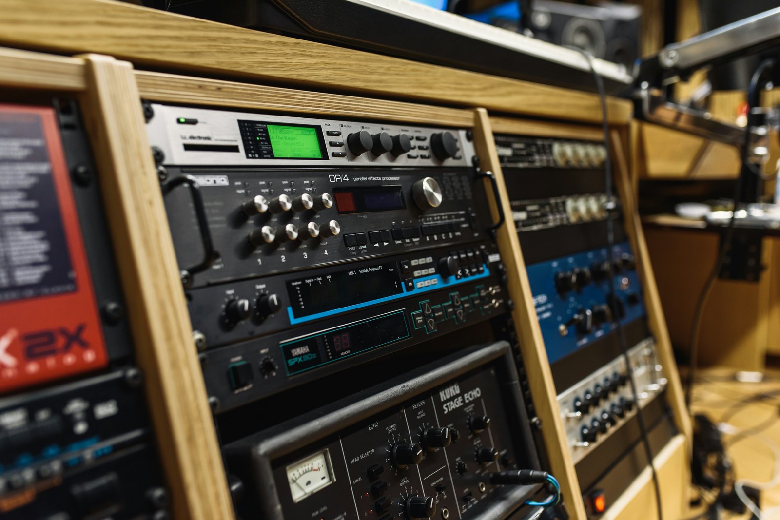 A black audio mixer on a brown wooden shelf in a music studio