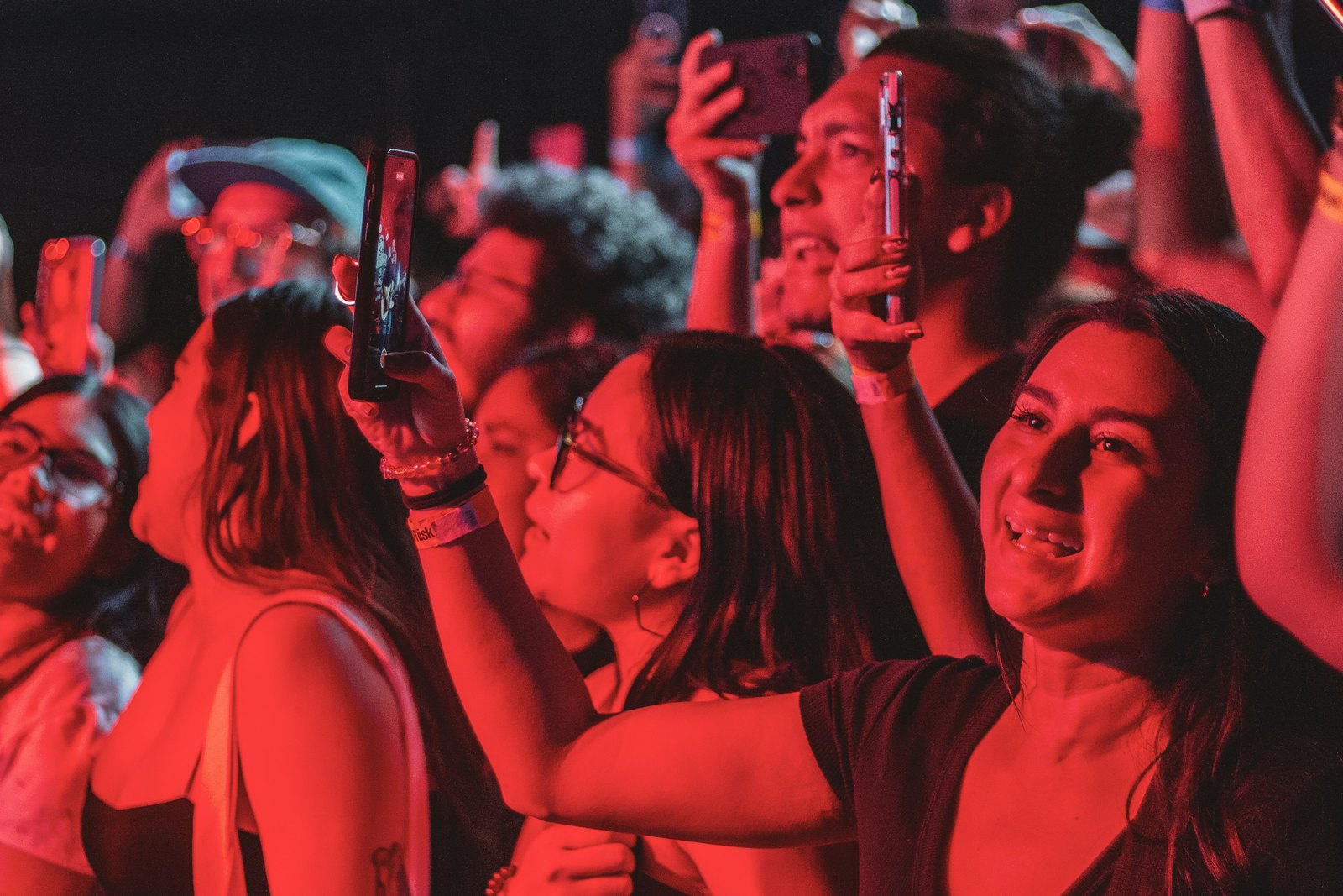 A concert crowd holding up smartphones to record the stage.