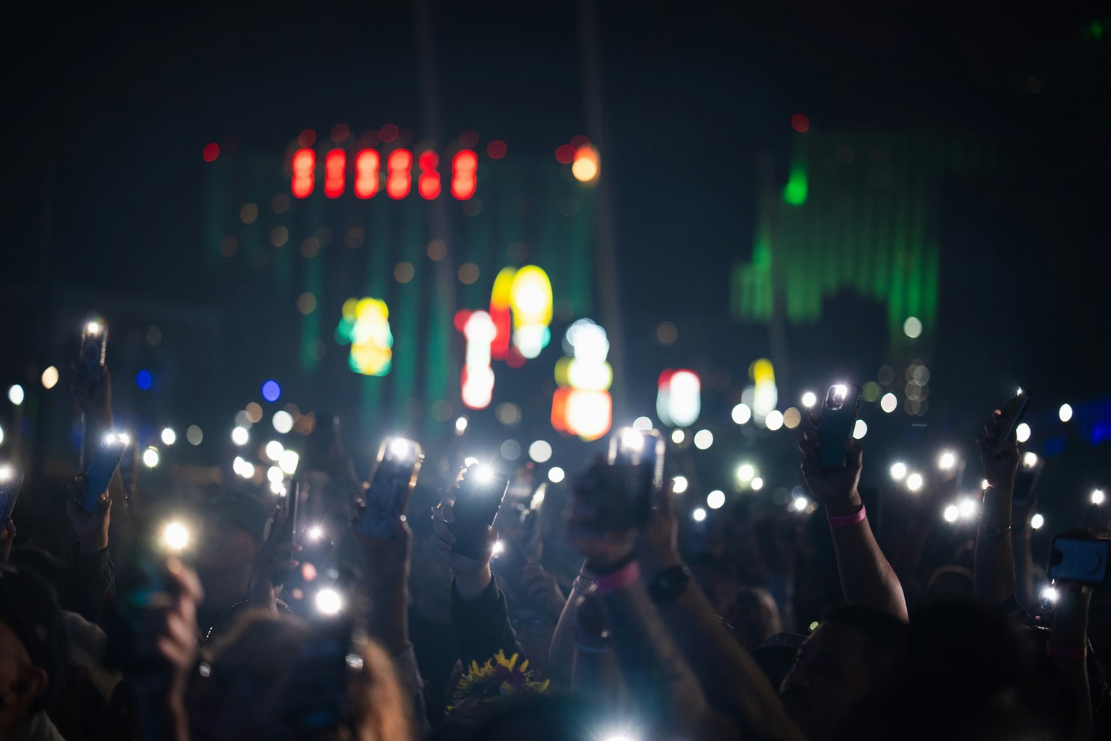 A concert crowd holding up their phones in the dark.