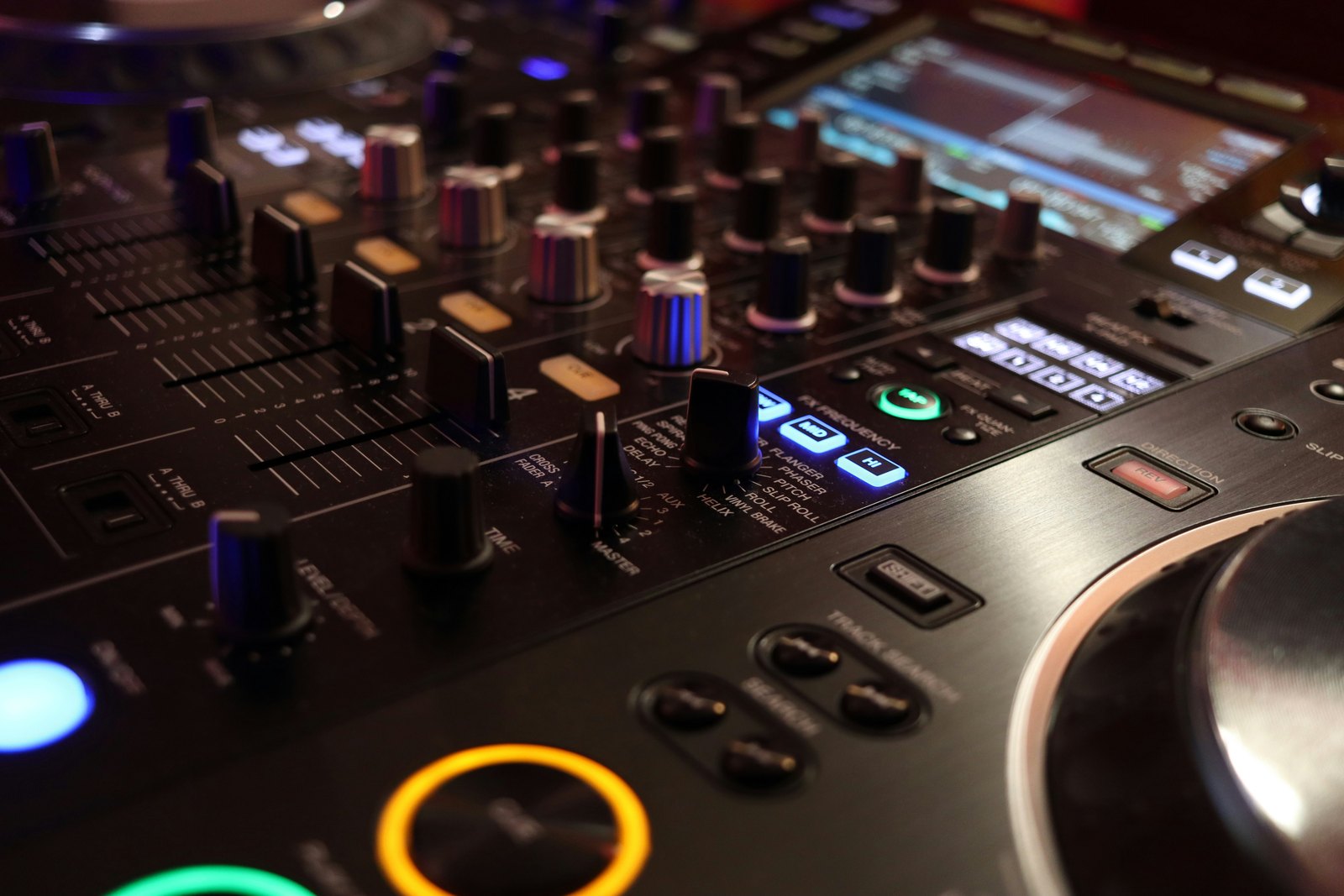 A close up of the buttons and knobs on a DJ control panel in low light.