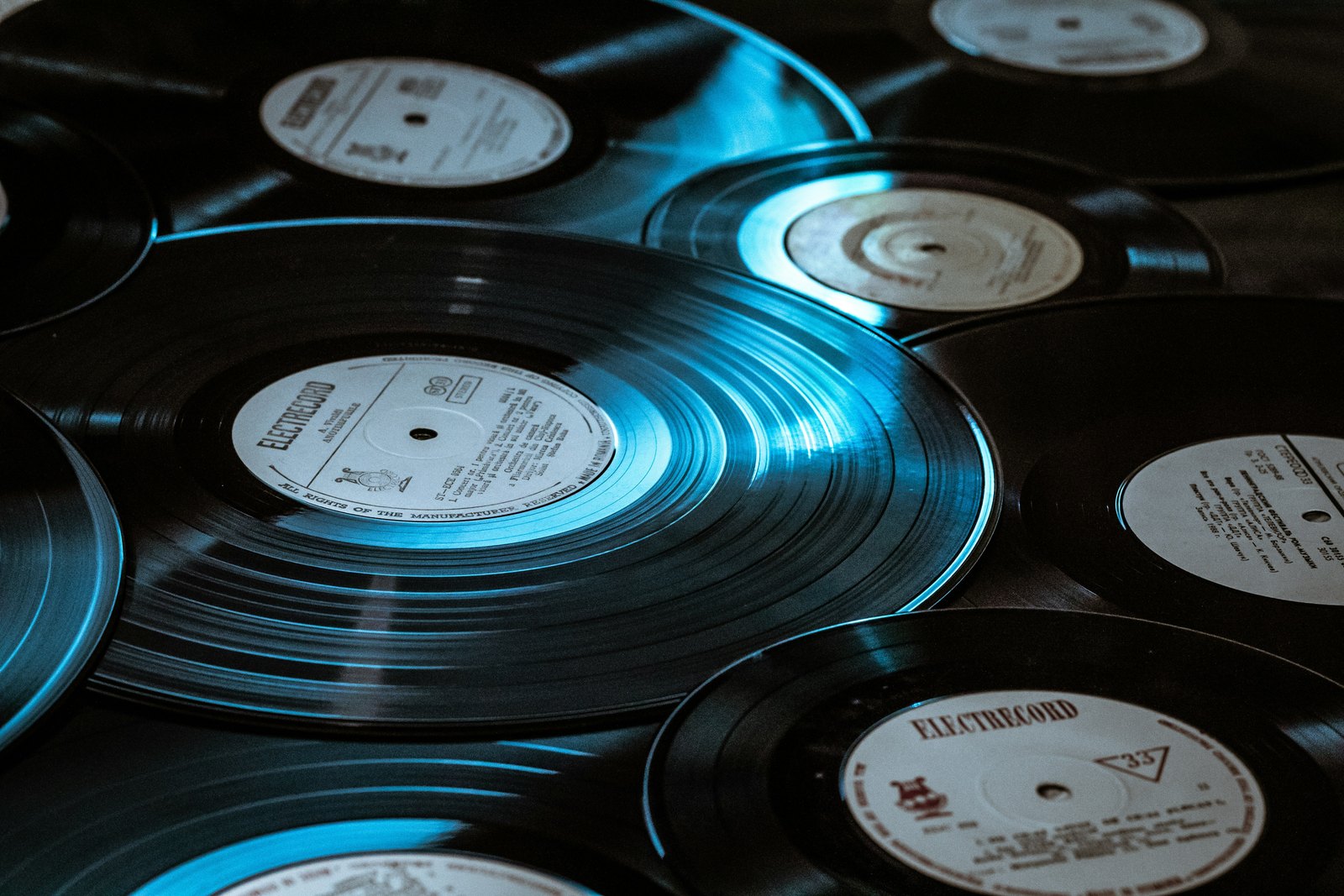 A close-up of a black vinyl record player in blue light