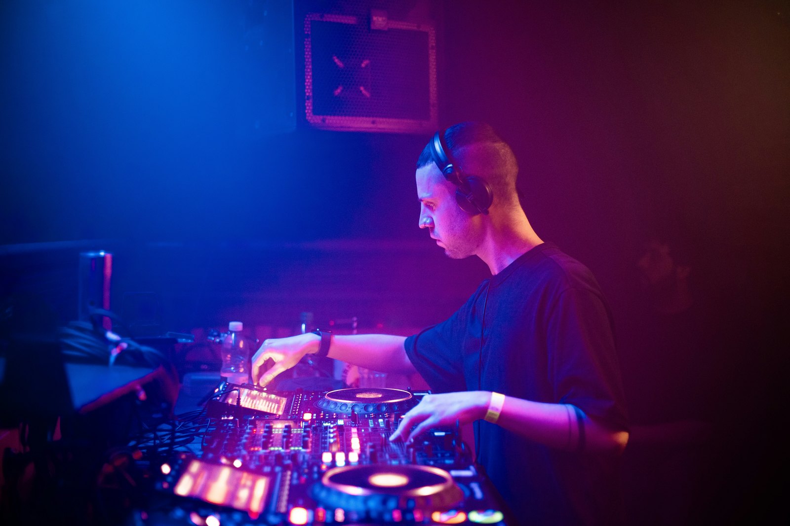 A DJ mixing music behind the decks in a dark room.