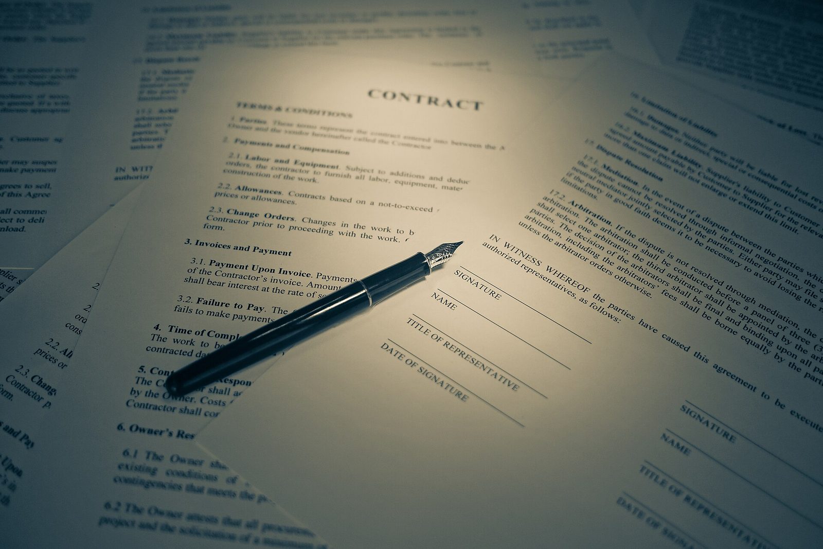 A close-up of a music distribution contract on a desk with key clauses highlighted and a pen resting beside a coffee cup.